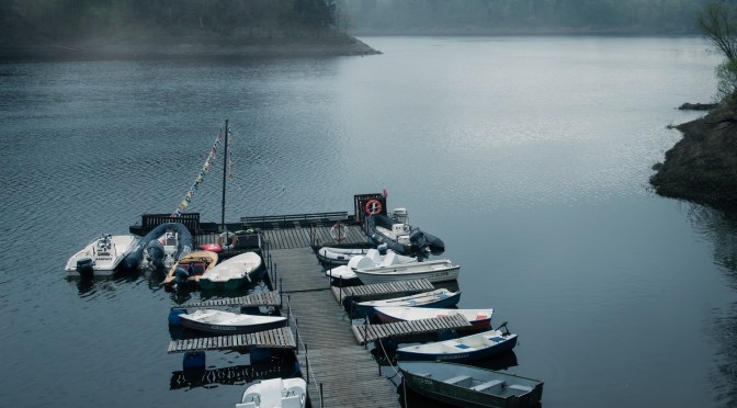 Moored boats in a quiet harbor on a foggy, peaceful morning