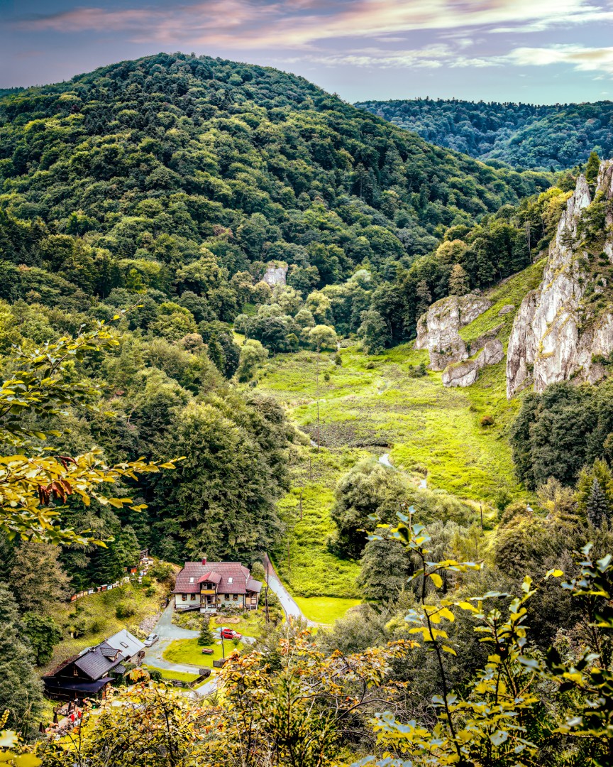 Green forested valley with scattered houses nestled below cliffs