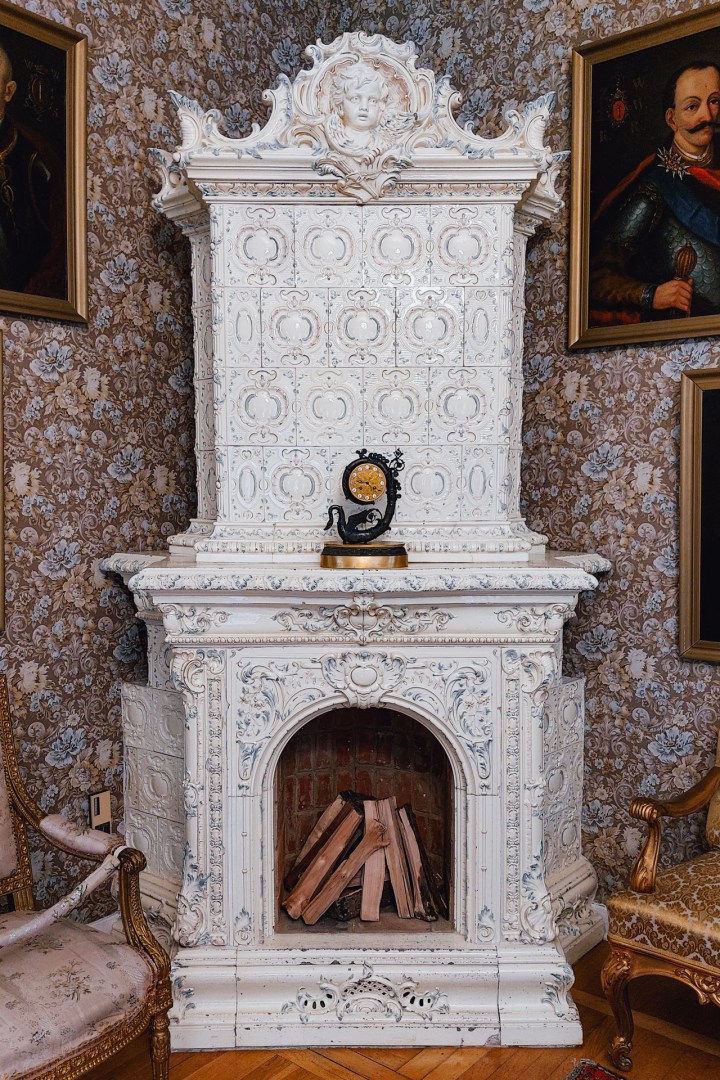 Elaborate white ceramic fireplace in the historic living room at Tubądzin Manor.