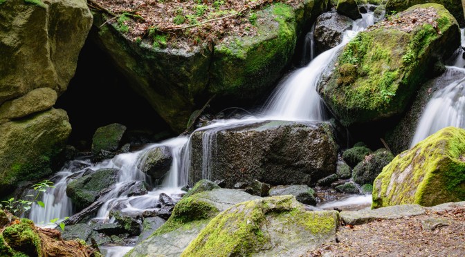 Small waterfall flowing over moss-covered rocks in the Land of Extinct Volcanoes, Lower Silesia, Poland