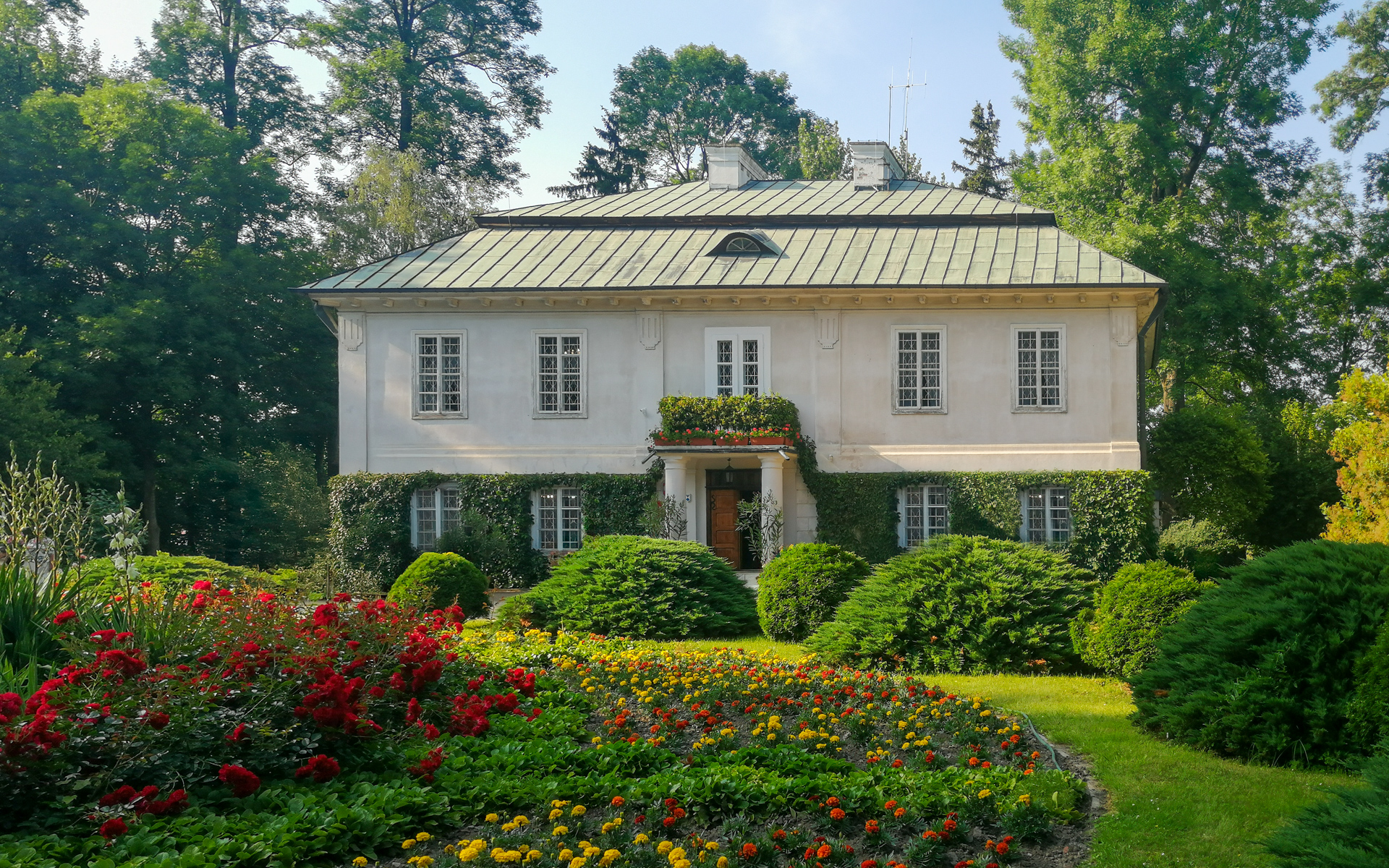 Classicist manor house of the Walewski family in Tubądzin, front view with flowers and trees