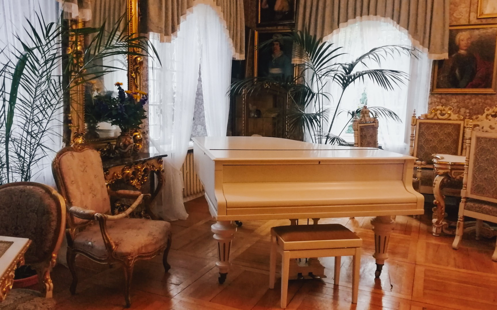 Period drawing room with white piano and elegant furnishings.