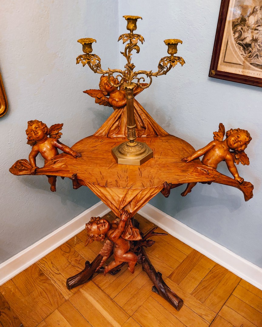 Unusual wooden candleholder table decorated with carved cherubs.