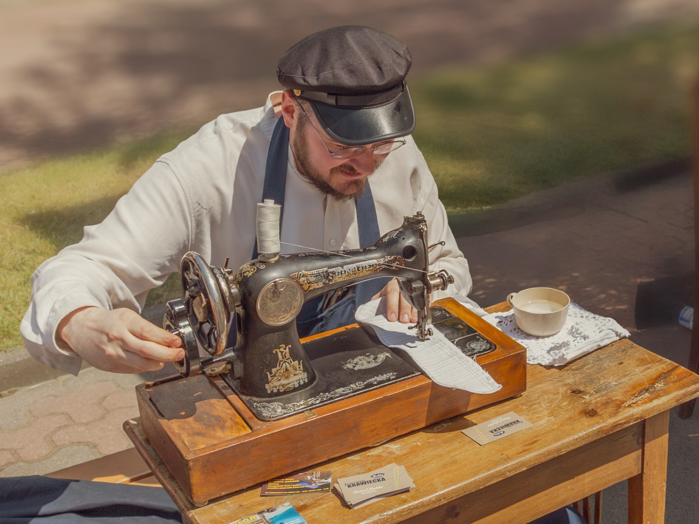 Craftsman using a vintage sewing machine at a Polish historical reenactment showing life in the 19th century