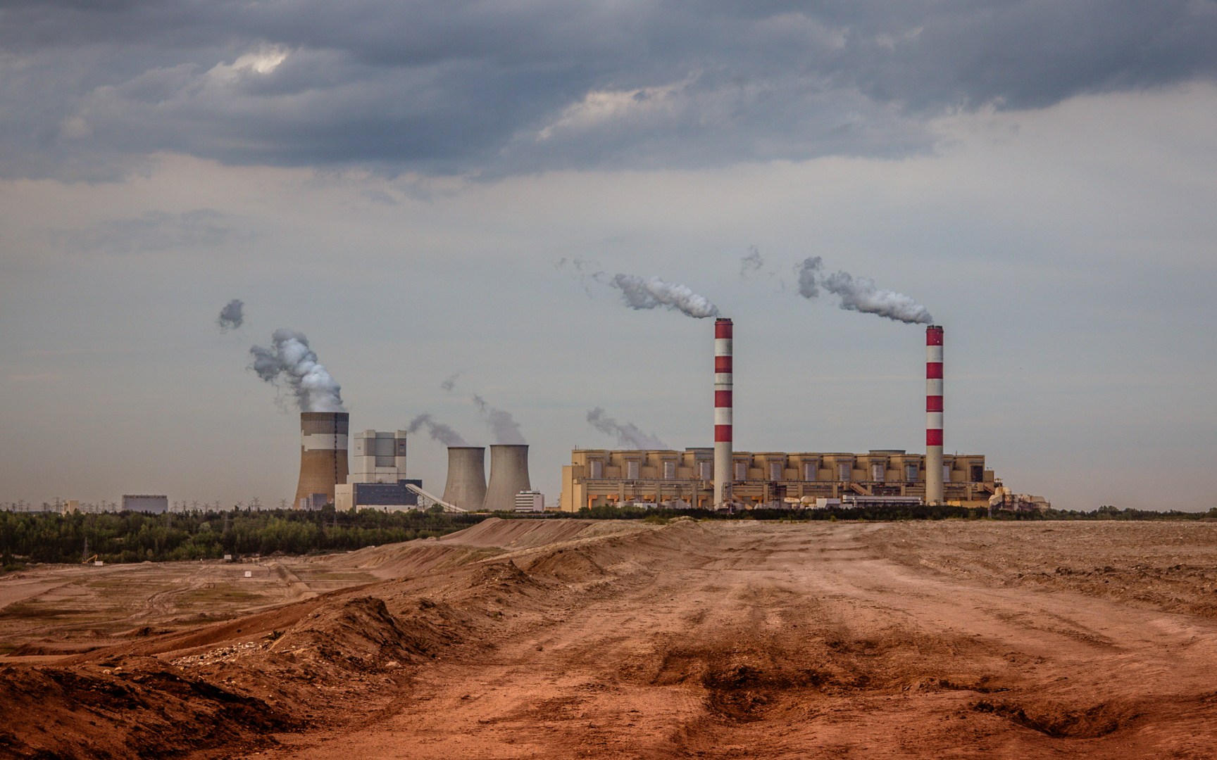 View of the Bełchatów lignite power plant in central Poland with smoking chimneys under a cloudy sky