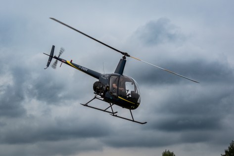 Black helicopter banking in a cloudy sky during an air show performance
