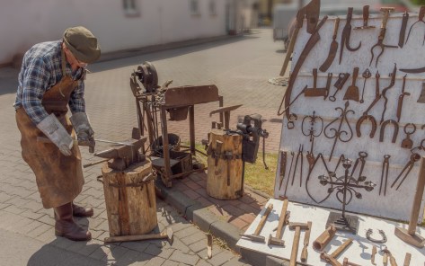 Man demonstrating traditional blacksmithing techniques with vintage tools during a 19th-century reenactment in Zduńska Wola