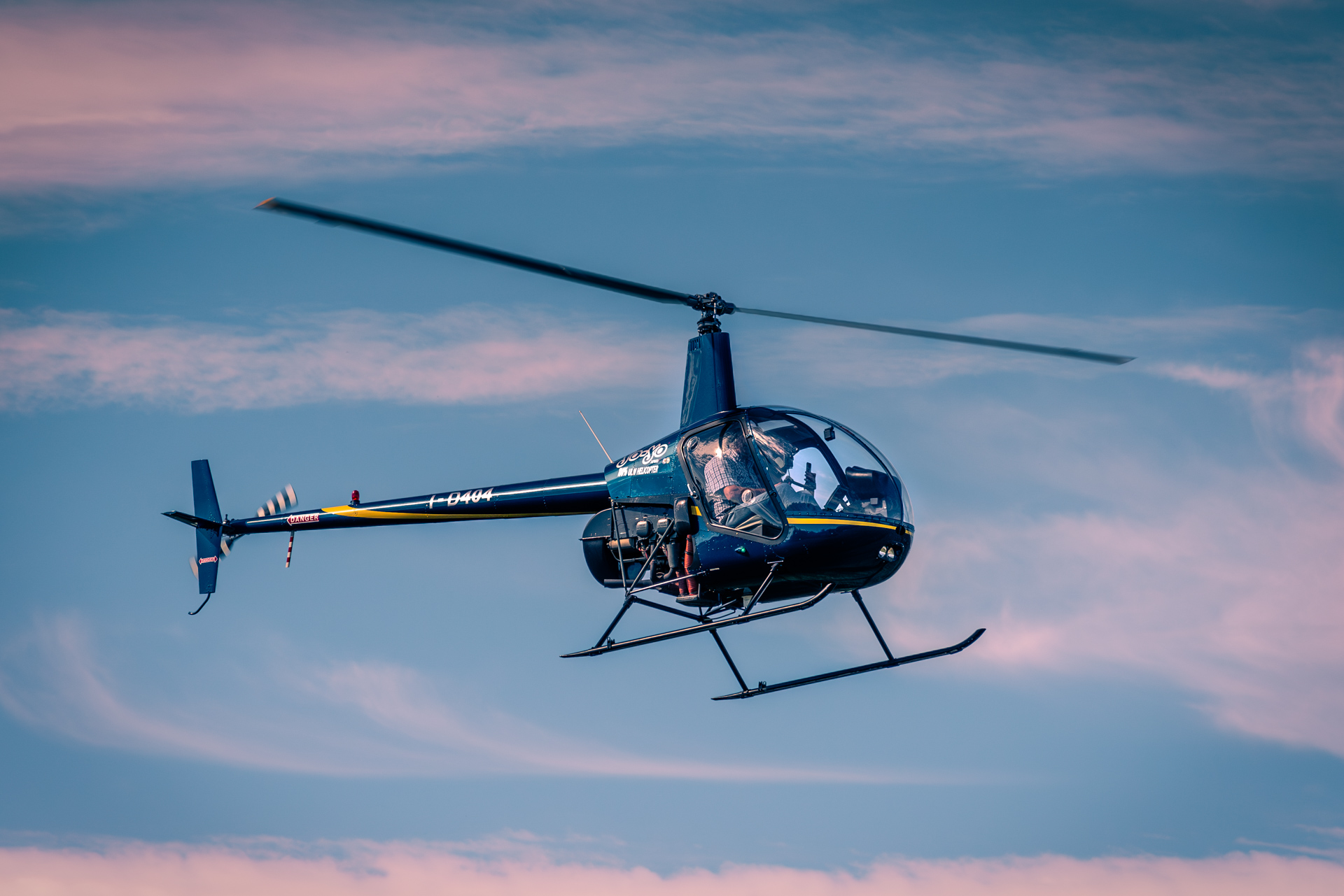 Helicopter flying against a pink and blue sunset sky