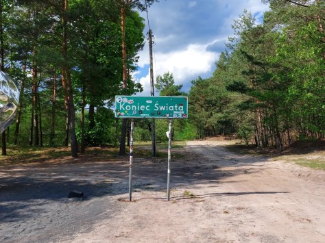 Green road sign marking Koniec Swiata, a popular cycling destination in the forest of central Poland
