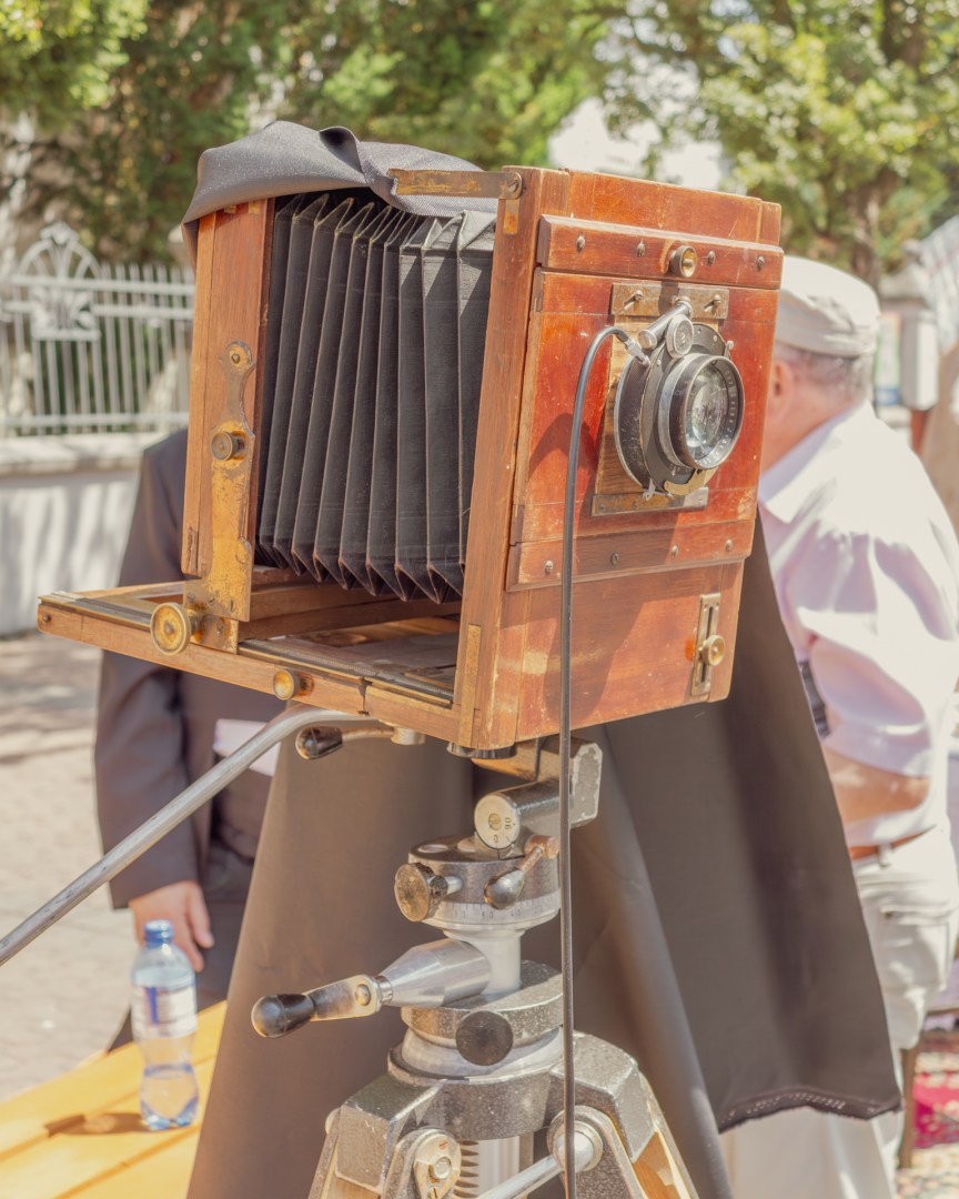Close-up of a large format wooden camera on a tripod, used in 19th-century portrait photography