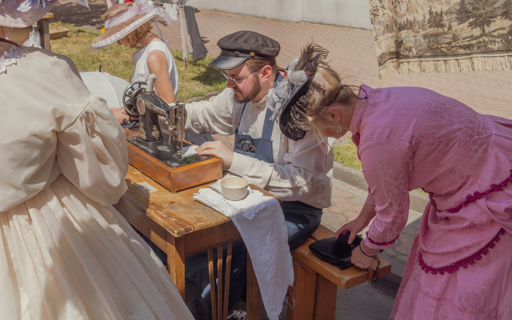 Men and women in vintage clothing demonstrating sewing and tailoring as part of a turn-of-the-century street festival in Poland
