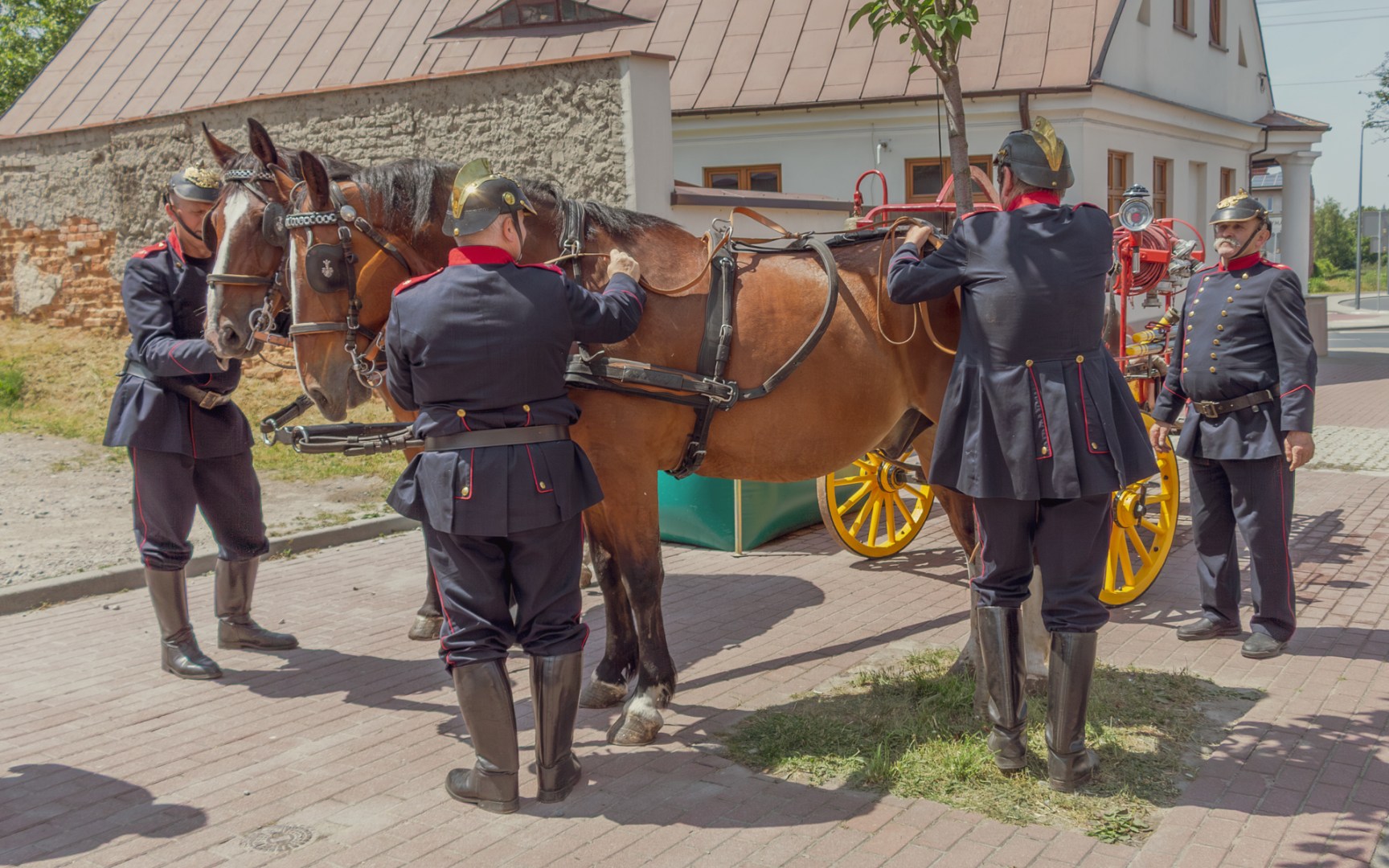 Firefighters in historical uniforms preparing a vintage horse-drawn fire carriage during a heritage event in Zduńska Wola