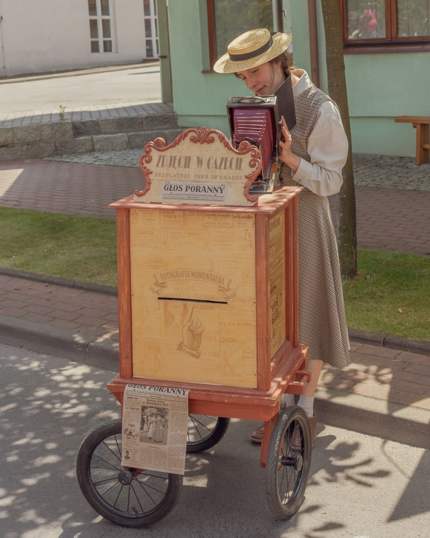 Woman in vintage clothing using an old-fashioned box camera to take and print portraits for visitors at a heritage event in Zduńska Wola