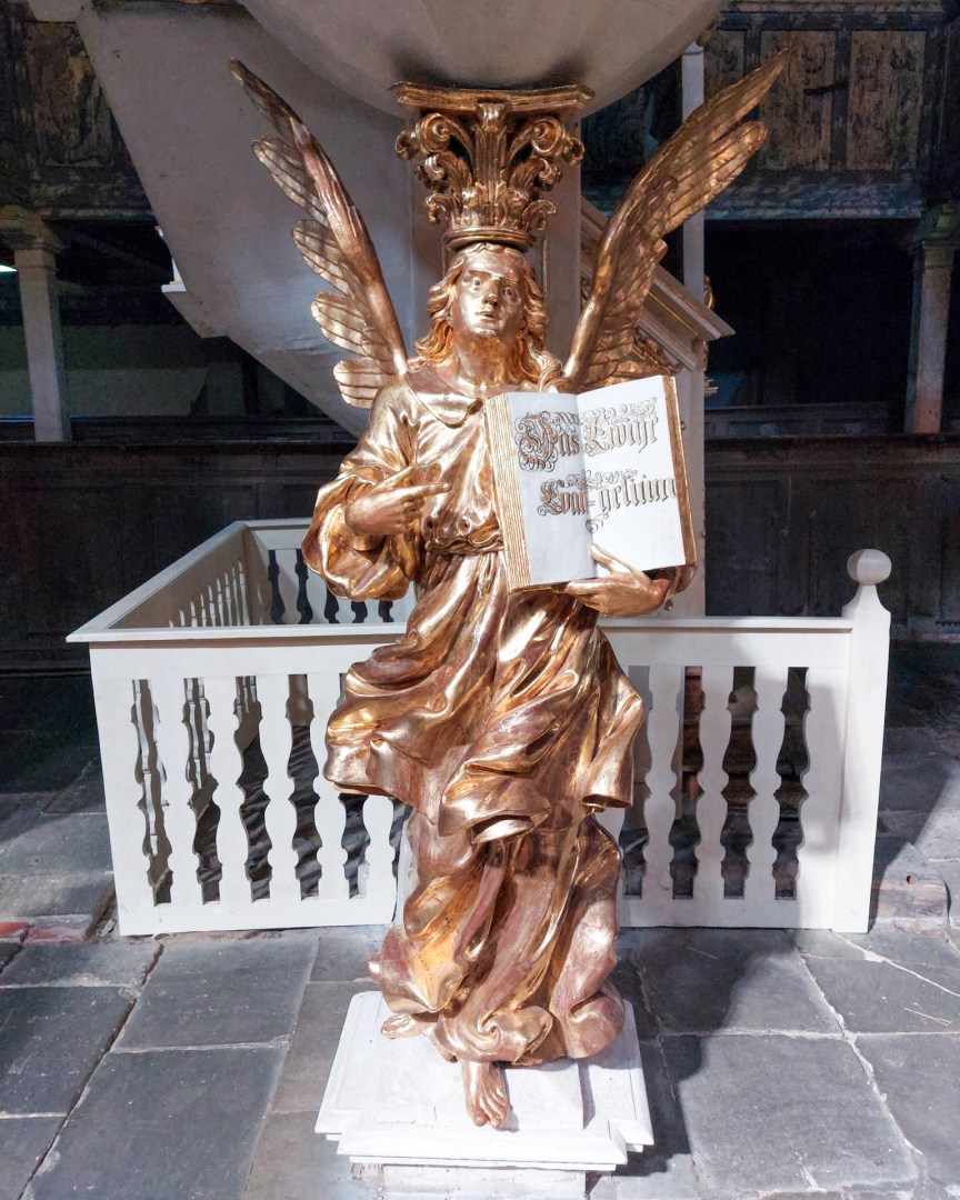 Golden Baroque angel sculpture holding an open book inside the Church of Peace, Jawor