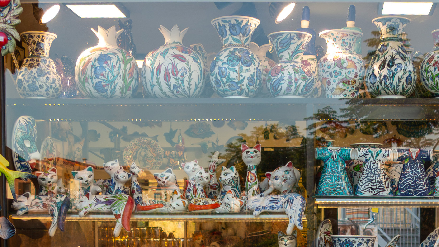 Upper part of a ceramic shop window showing pottery and ornaments with visible street reflections on the glass