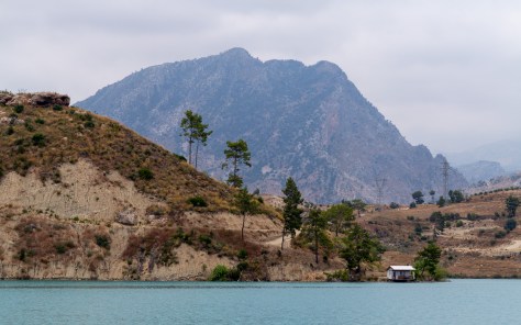 A lakeside hut framed by orange hills and a towering mountain in Turkey