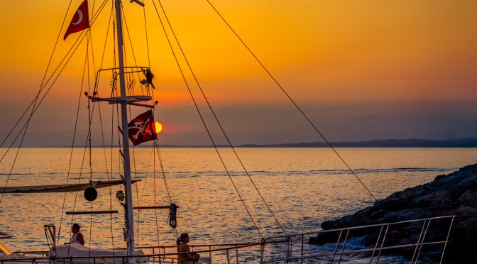 Sailing boat with Turkish flags at sunset on the Mediterranean Sea