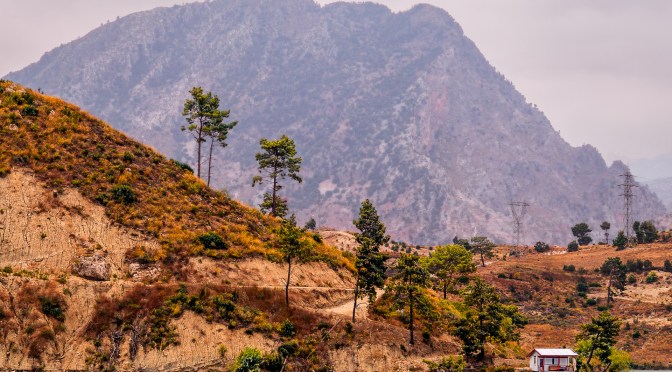 A small hut by a turquoise lake in Turkey, framed by orange hills and a towering mountain