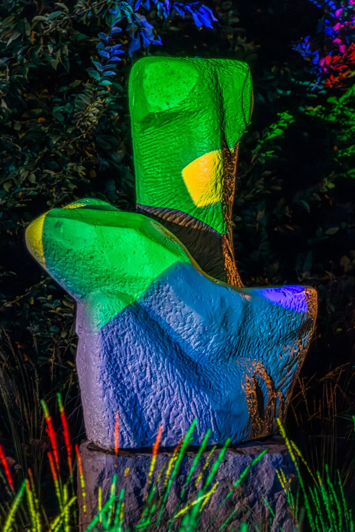 Two bright green illuminated statues surrounded by plants during the Light Move Festival in Łódź